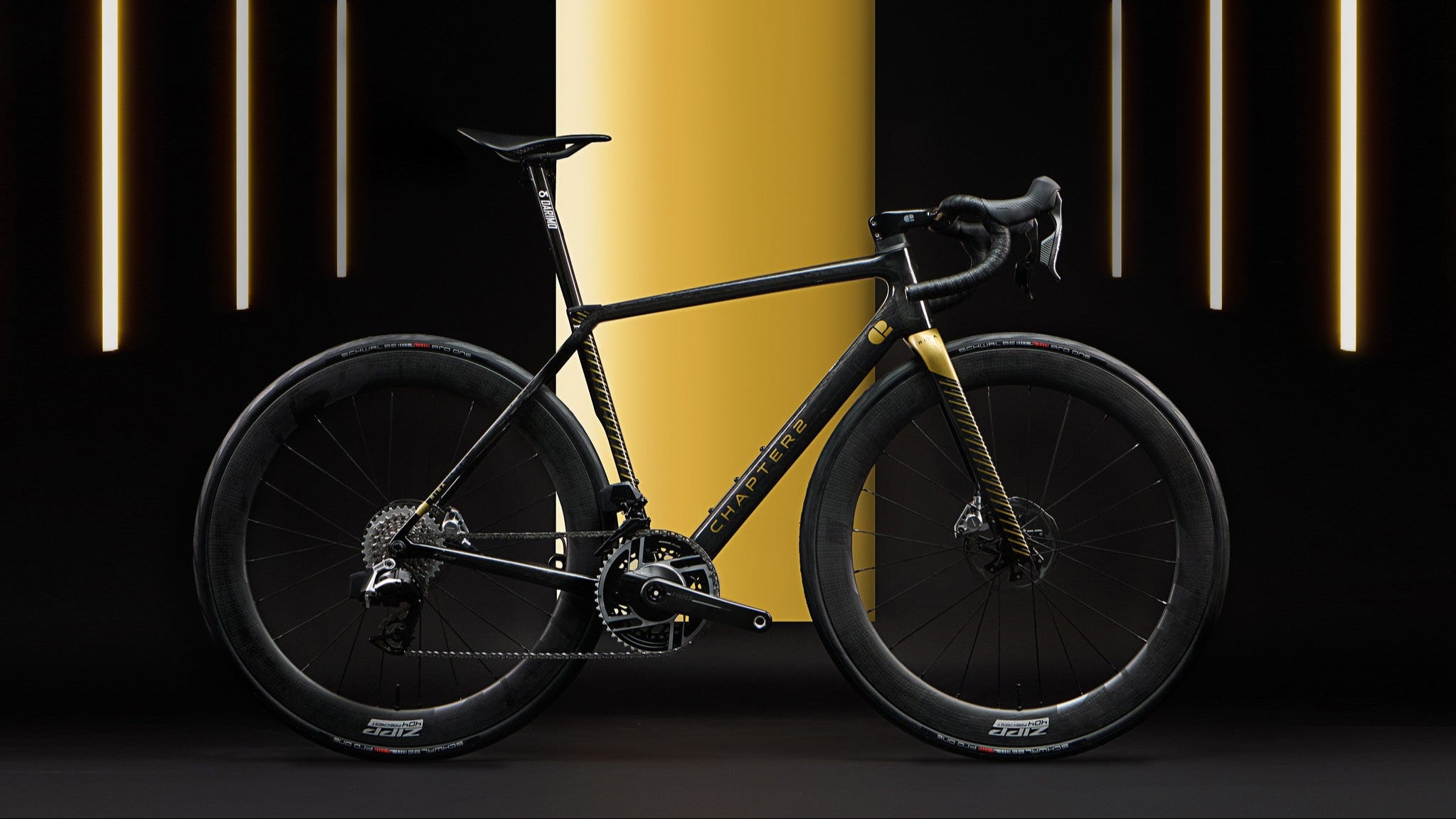 Black bicycle on a dark background with a yellow cylindrical object and vertical lights.